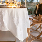 Elegant table setting with a white tablecloth and decorative items in a softly blurred indoor setting.