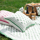 Picnic setup with a blanket, pillows, and a basket on grass