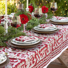 Decorative table setting with red and white patterned tablecloth, wine glasses, and floral arrangements.