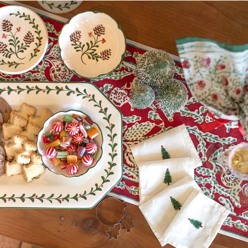 Decorative Christmas table setting with plates, candy, and napkins on a red patterned tablecloth.
