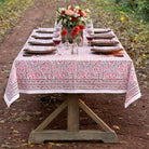Dining table set with a pink and white patterned tablecloth outdoors.