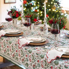 Decorative Christmas table setting with floral centerpieces, wine glasses, and a tree in the background.