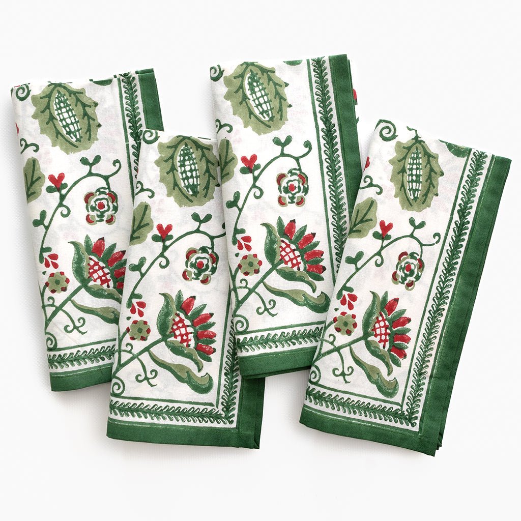 Set of four napkins with green and red floral patterns on a white background