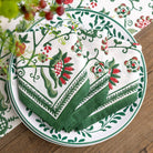 Decorative plate with green and red floral patterned napkins on a wooden surface