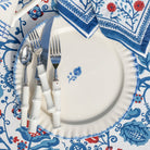 Decorative table setting with white plates, silverware, and a patterned napkin.