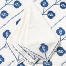 White fabric with blue fish and pomegranate pattern, folded on a white background