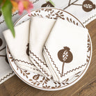 Decorative plate with pomegranate design and matching napkins on a wooden surface.