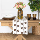 Table setting with a floral arrangement, tortoiseshell-patterned vase, and decorative table runner.