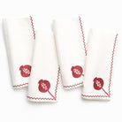 Set of four white napkins with burgundy embroidery on a white background