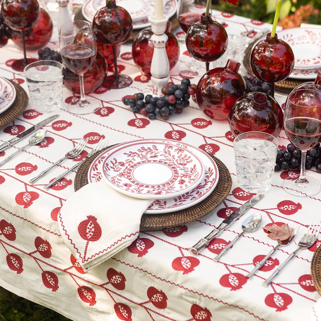 Dining table set with red and white tablecloth, wine glasses, and silverware.
