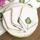Set of white napkins with green leaf design on a matching plate.
