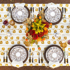 Elegant table setting with decorative plates, cutlery, and a floral centerpiece on a patterned tablecloth.
