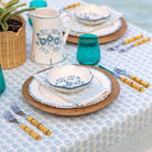 Table setting with blue and white floral-patterned dishes on a patterned tablecloth.