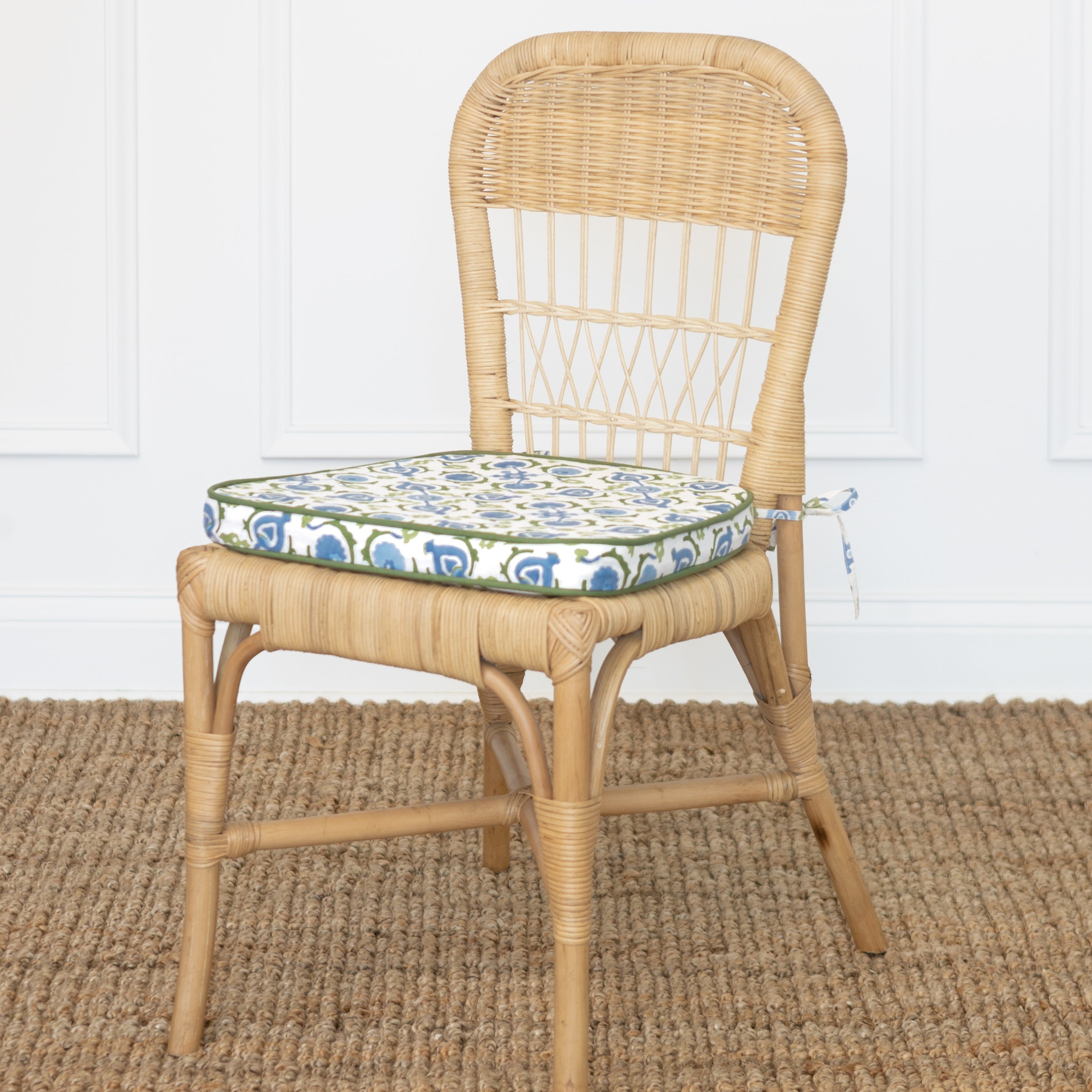 Wicker chair with a patterned cushion on a textured floor.