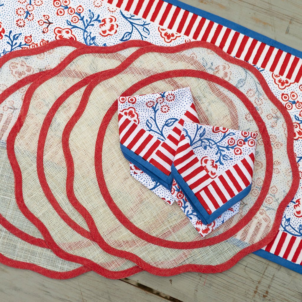 Set of red, white, and blue placemats and napkins on a wooden surface with floral patterns.
