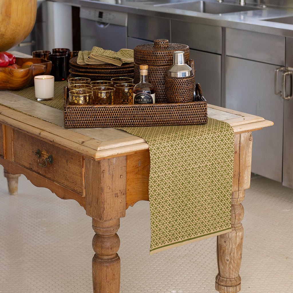 Wooden table with a green runner, candles, and decorative items in a kitchen setting.