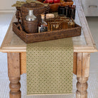 Wooden table with a woven tray containing bar items and a green patterned table runner.