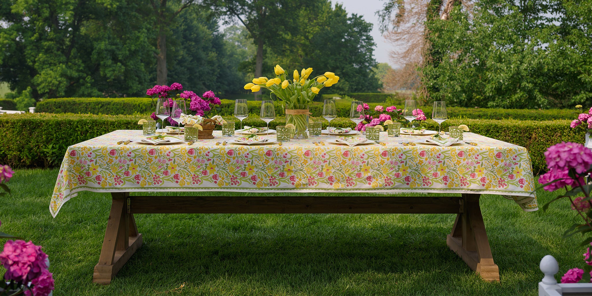 Decorated table outdoors with floral tablecloth and centerpieces.