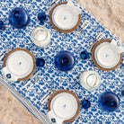 Table setting with blue and white decor on a floral tablecloth.