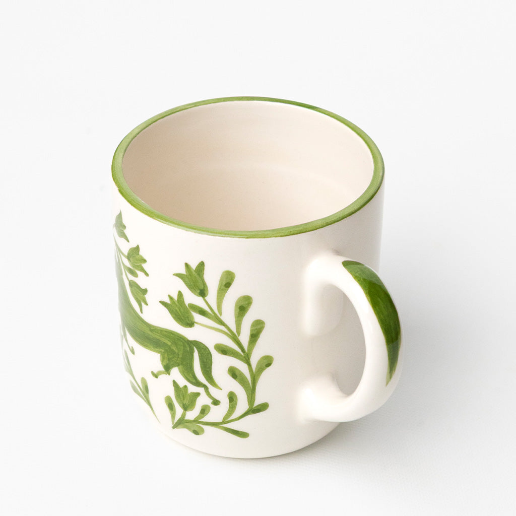 White ceramic mug with green horse and floral design.