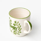 White ceramic mug with green horse and floral design.