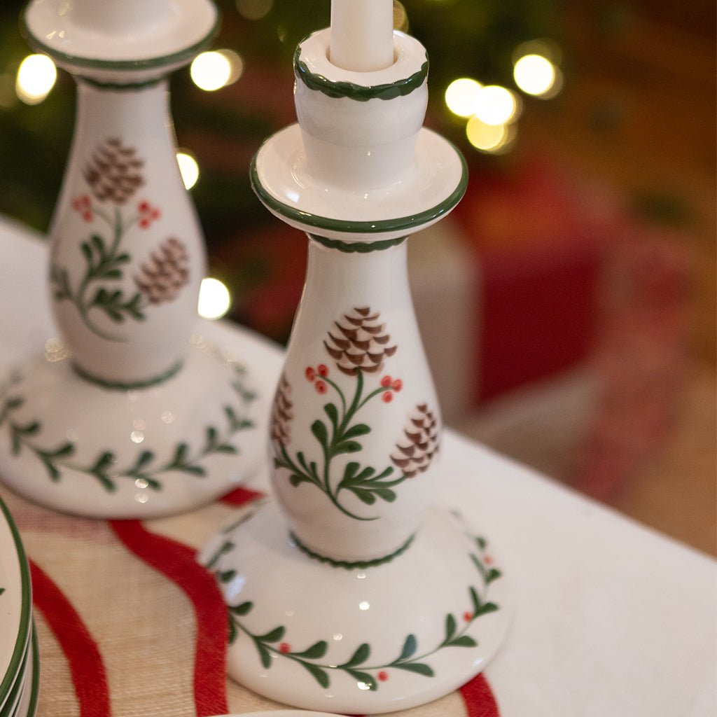 Decorative ceramic candlestick with floral patterns on a tablecloth with blurred lights in the background