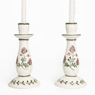 Pair of white candle holders with floral design on a white background