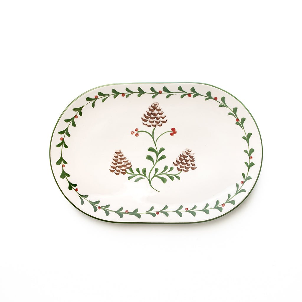 Decorative oval plate with floral and pine cone design on a white background