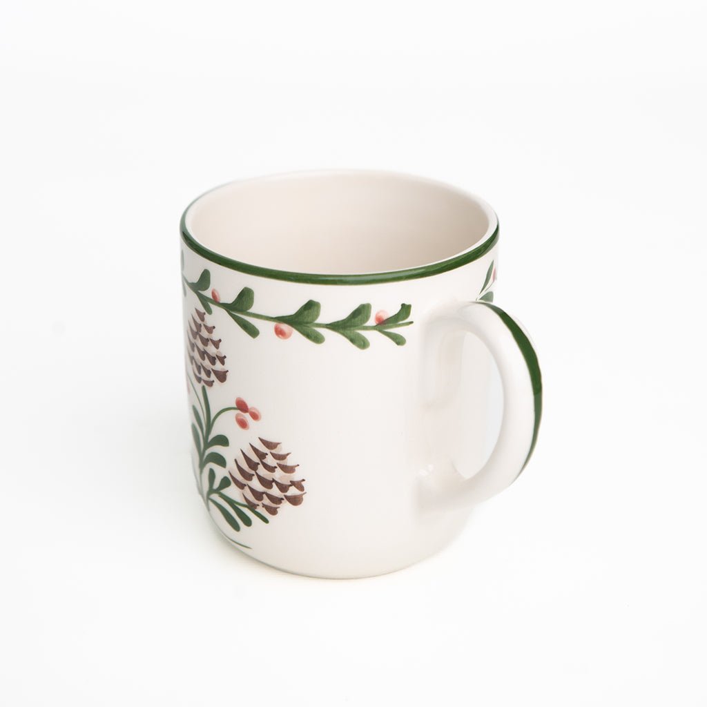 White mug with green rim and floral design on a white background