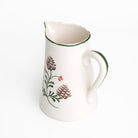 Ceramic pitcher with floral design on a white background