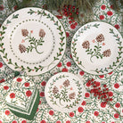 Set of ceramic plates with floral and pine cone design on a patterned background.