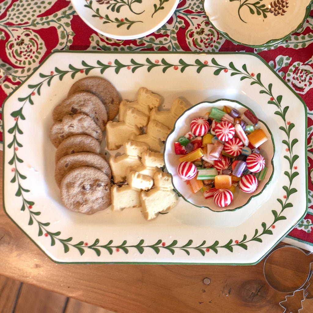 Decorative plate with cookies and a bowl of candies on a festive tablecloth.