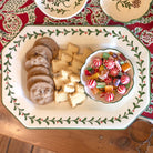 Decorative plate with cookies and a bowl of candies on a festive tablecloth.