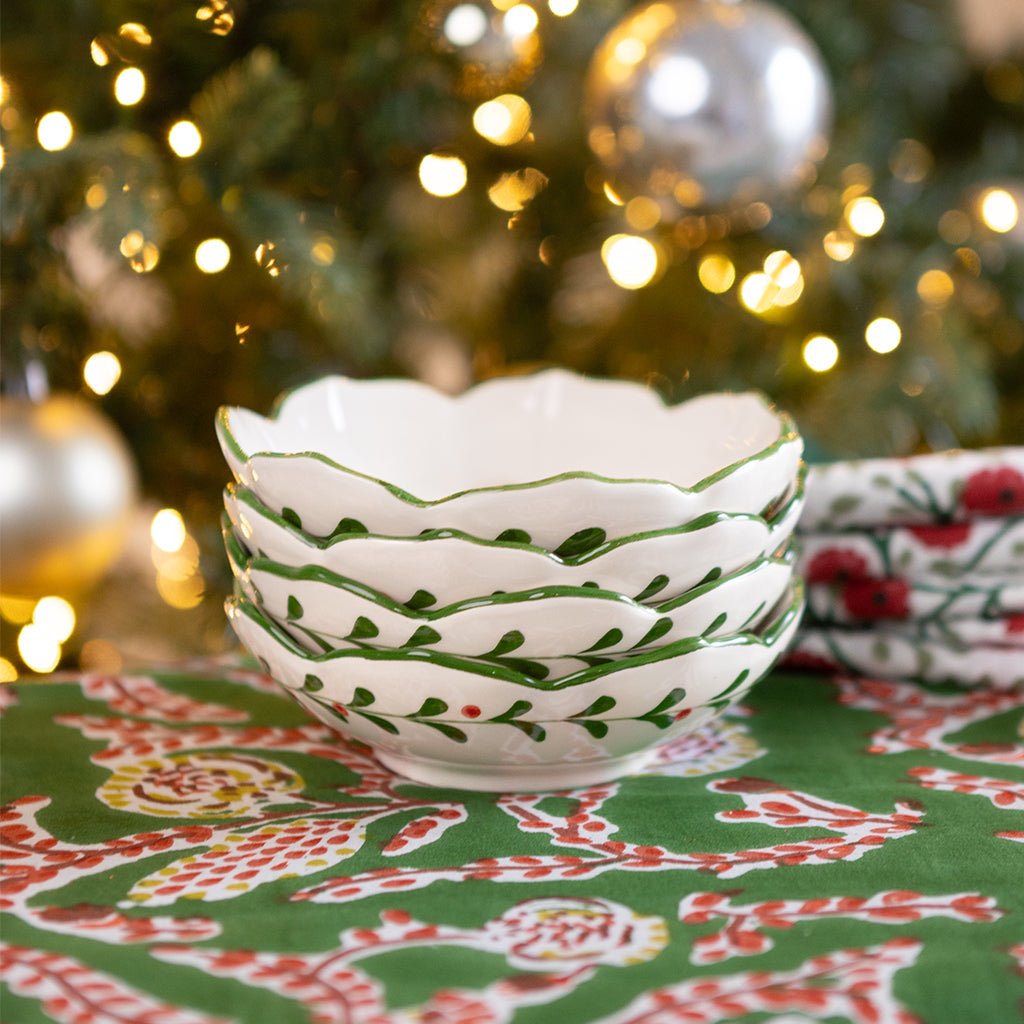 Decorative white bowl with green patterns on a festive tablecloth with Christmas tree in the background