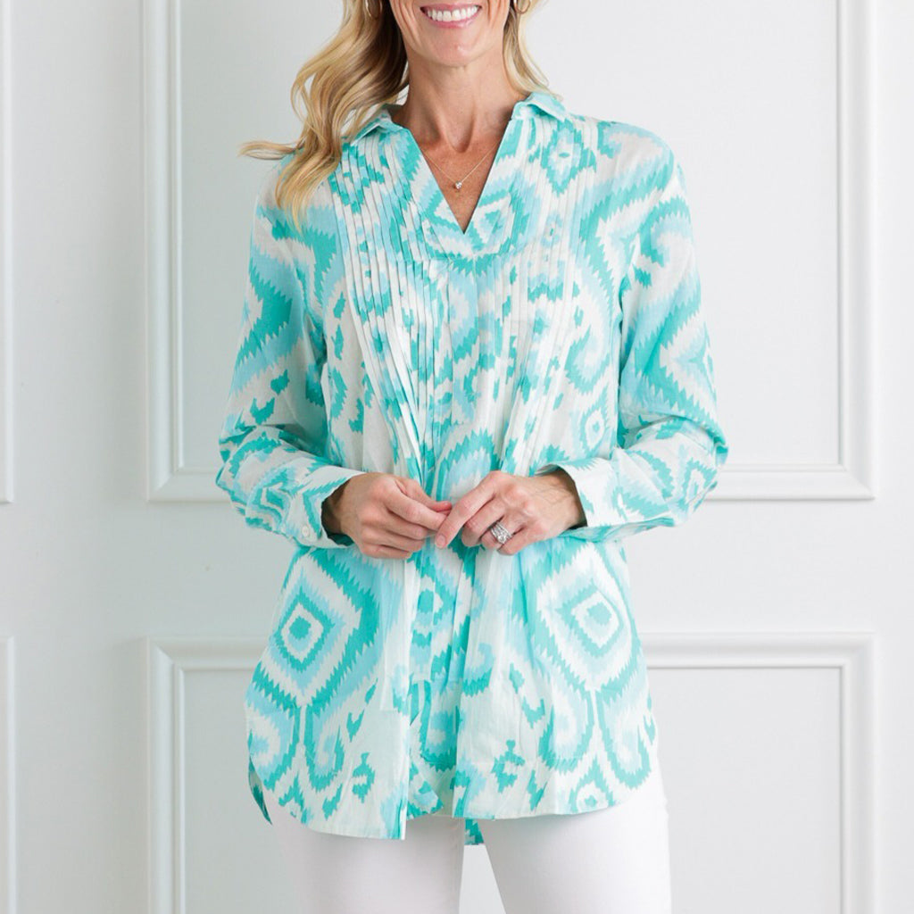 Woman wearing a turquoise and white patterned blouse against a white background