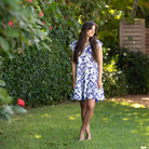 Woman in a blue and white patterned dress standing in a garden.