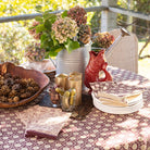 Decorative table setting with flowers, candles, and a red fox figurine on a patterned tablecloth.