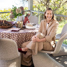 Woman sitting at a table outdoors with a floral arrangement and candles.