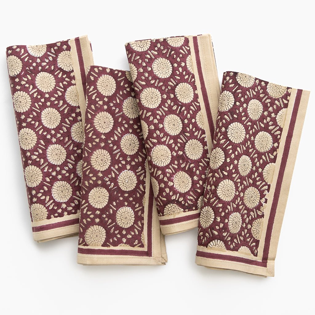 Set of four maroon and beige patterned napkins on a white background