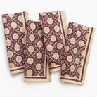 Set of four maroon and beige patterned napkins on a white background