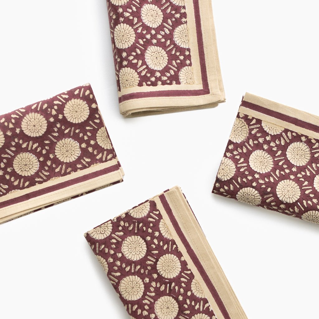 Set of four folded fabric napkins with a floral pattern on a white background