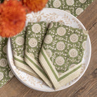 Green and beige patterned napkins on a white plate with a wooden background