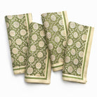 Set of four green and beige patterned napkins on a white background