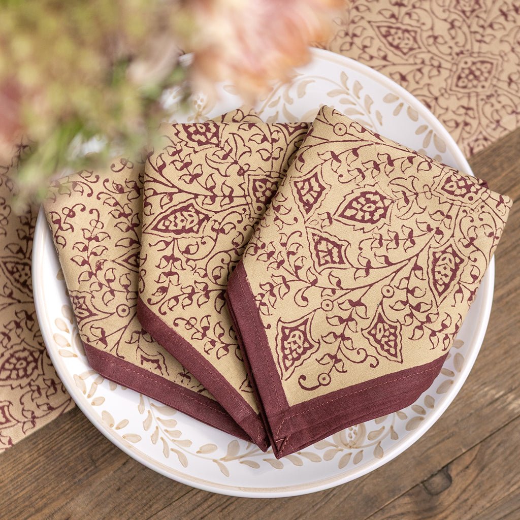 Three patterned napkins on a white plate with a wooden background
