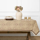 Tablecloth with floral pattern on a wooden table against a white paneled wall.