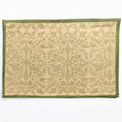Decorative mat with green border and intricate pattern on beige background