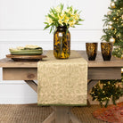 Dining table set with a vase of flowers, plates, and glasses in front of a decorated Christmas tree.