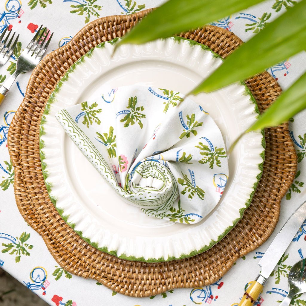 Plated dish with a folded napkin on a woven placemat over a patterned tablecloth.