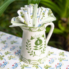Decorative pitcher filled with patterned paper on a tablecloth with bicycle design.