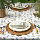 Dining table setting with floral tablecloth, plates, cutlery, and glasses.